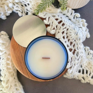 Top view of yellow harp essentials highly scented old-fashioned gingerbread candle in glass blue jar with silver metal lid. ￼